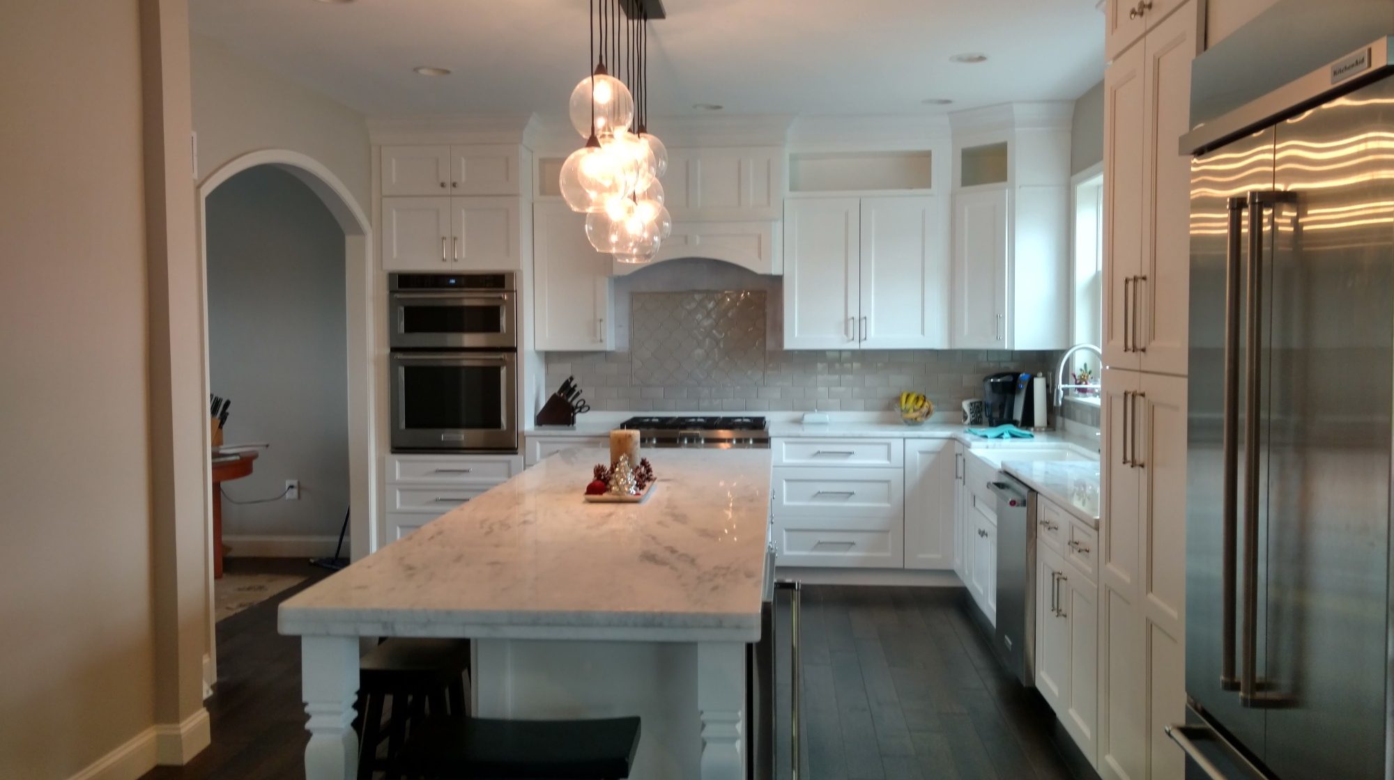 Bright modern kitchen with white cabinetry, marble island, and stainless steel appliances.