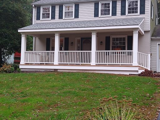 Two-story house with a white porch, green lawn, and blue shutters.