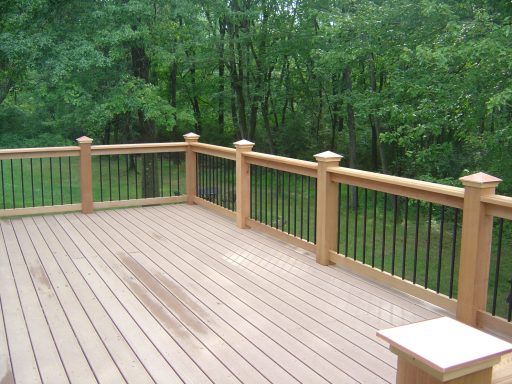 A wooden deck with a railing overlooking a green forested area.
