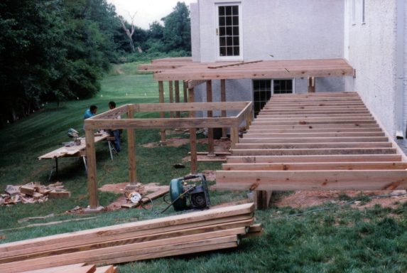 Construction of a wooden deck underway, with workers and materials visible.