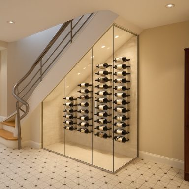 Modern wine cellar under stairs with glass enclosure and neatly arranged wine bottles.