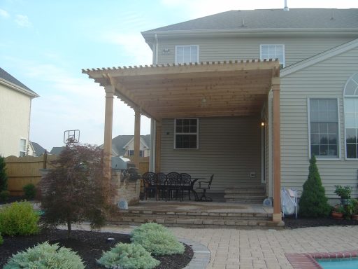 Back patio with wooden pergola, outdoor seating, and landscaped garden area.