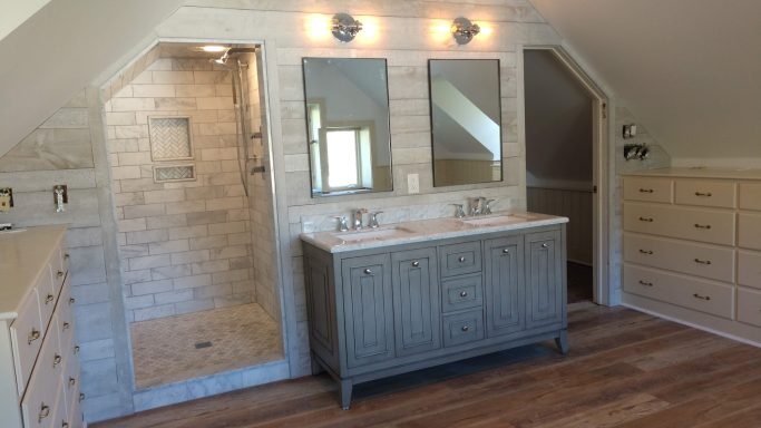 Modern bathroom featuring dual sinks, mirrors, a glass shower, and wooden cabinetry.