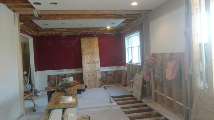 A partially renovated room with red walls and exposed wooden beams, tools, and materials.
