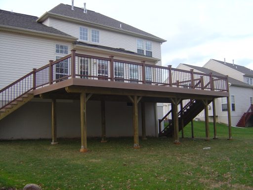 Two-story wooden deck attached to a house, with steps leading to the ground.
