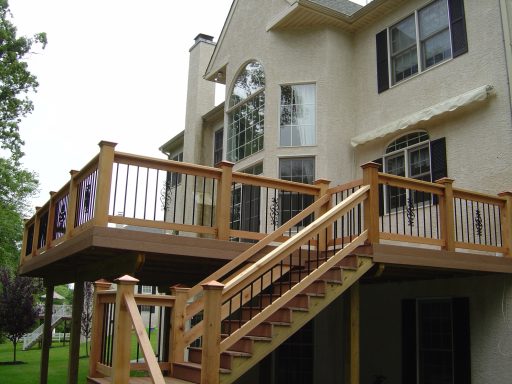 Two-story house with a wooden deck and stairs leading to the backyard.